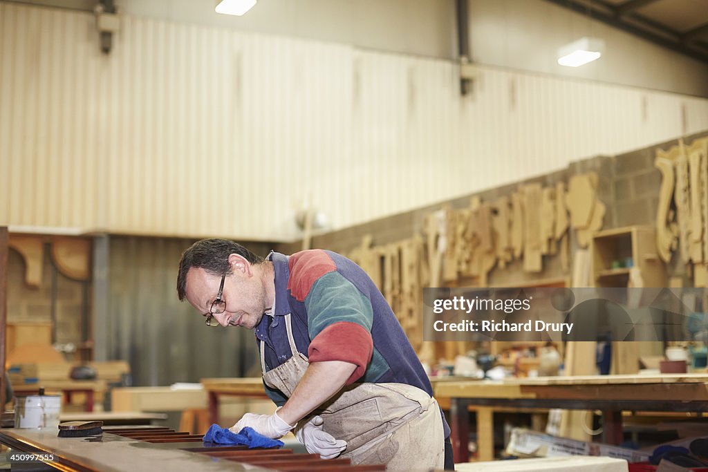 Craftsman applying wax finish to furniture
