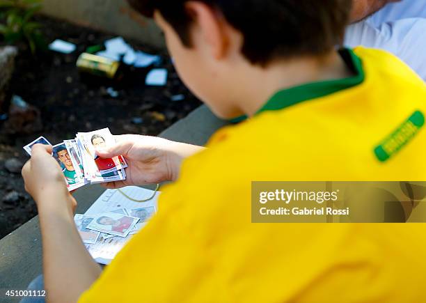 Kid wearing the Brazilian jersey counts his Panini 2014 FIFA World Cup Brazil stickers at Praça Popular on June 21, 2014 in Cuiaba, Brazil.
