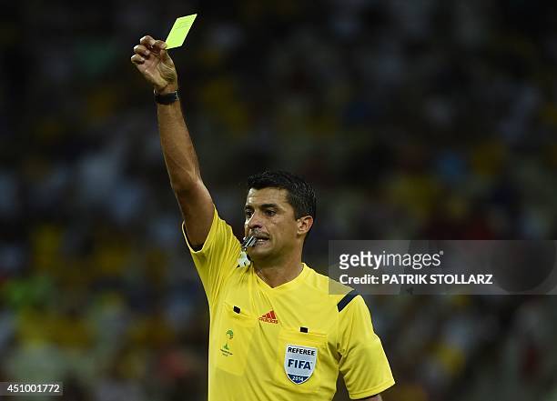 Brazilian referee Sandro Meira Ricci shows a yellow card during a Group G football match between Germany and Ghana at the Castelao Stadium in...