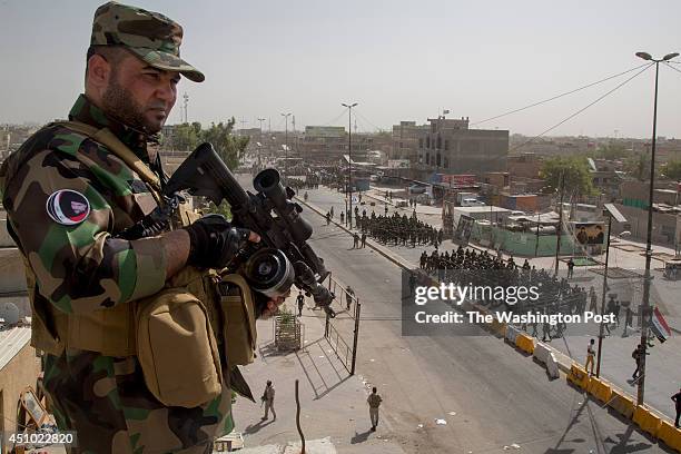 Sadr militiamen stands guard on a rooftop as units of Moqtada Sadr's militia parade down a main street of the Shi'a stronghold of Sadr City June 21,...