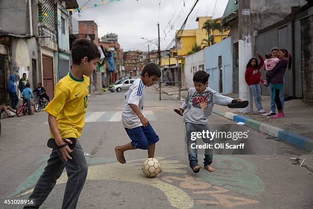 Children play football in the street in the poor neighbourhood of Itaquera, adjacent to the 'Arena de Sao Paulo' stadium, on June 21, 2014 in Sao...