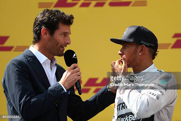 Lewis Hamilton of Great Britain and Mercedes GP speaks with former F1 driver Mark Webber on the podium after finishing second in the Austrian Formula...