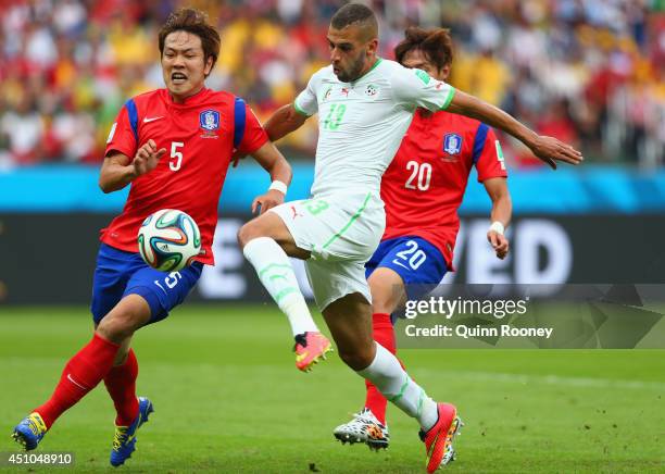 Islam Slimani of Algeria scores his team's first goal against Kim Young-Gwon and Hong Jeong-Ho of South Korea during the 2014 FIFA World Cup Brazil...