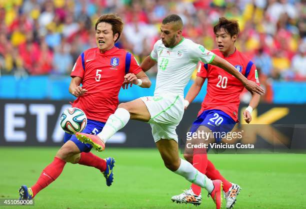 Islam Slimani of Algeria scores his team's first goal against Kim Young-Gwon and Hong Jeong-Ho of South Korea during the 2014 FIFA World Cup Brazil...