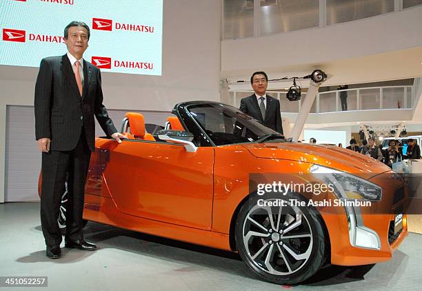 Daihatsu Motor Co President Masanori Mitsui poses for photographs with 'Kopen' open-top sports car during the 43rd Tokyo Motor Show at Tokyo Big...