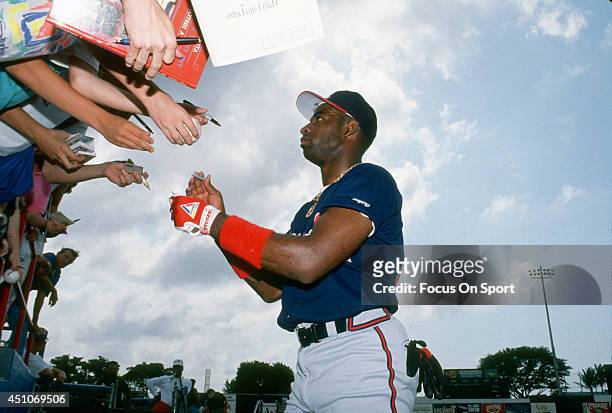 Deion Sanders of the Atlanta Braves signs autographs for fans prior to a Major League Baseball spring training game circa 1993. Sanders played for...