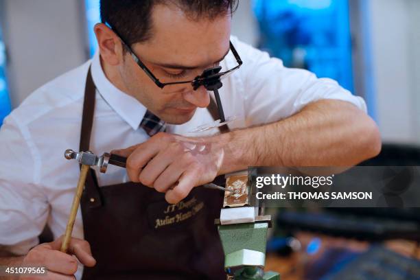 An employee of the ST Dupont luxury company works on a lighter on November 21, 2013 in Paris. AFP PHOTO / THOMAS SAMSON