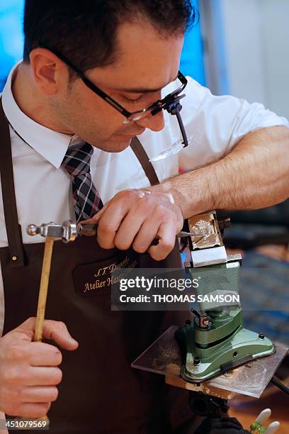 An employee of the ST Dupont luxury company works on a lighter on November 21, 2013 in Paris. AFP PHOTO / THOMAS SAMSON