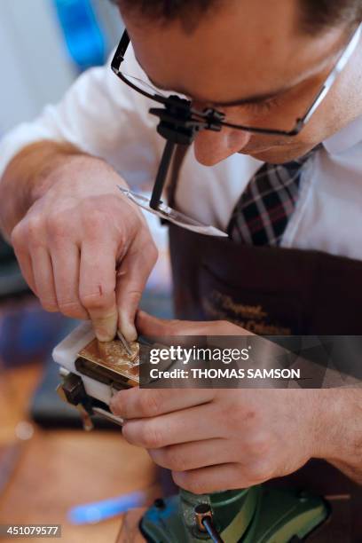 An employee of the ST Dupont luxury company works on a lighter on November 21, 2013 in Paris. AFP PHOTO / THOMAS SAMSON