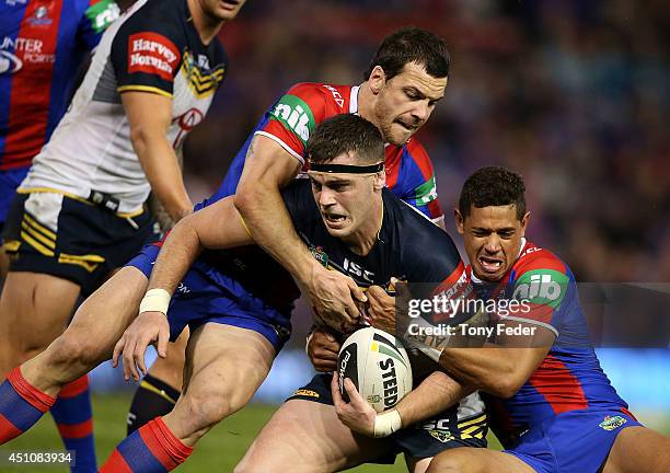 Ethan Lowe of the Cowboys is tackled by the Knights defence during the round 15 NRL match between the Newcastle Knights and the North Queensland...