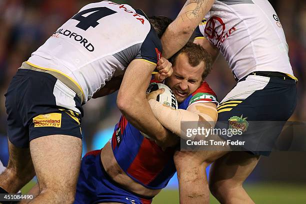 Clint Newton of the Knights is tackled by the Cowboys defence during the round 15 NRL match between the Newcastle Knights and the North Queensland...