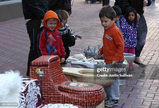 Children look at decorated toilets that are part of a public art installation titled "C'mon, give a shit" to mark World Toilet Day and to bring...