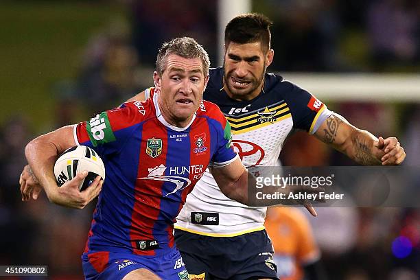 Chris Houston of the Knights is tackled by James Tamou of the Cowboys during the round 15 NRL match between the Newcastle Knights and the North...