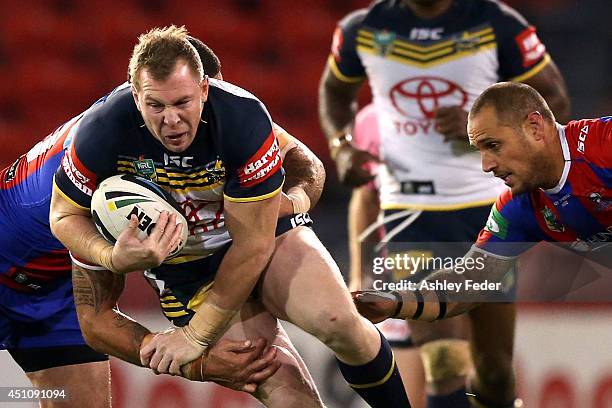 Glenn Hall of the Cowboys is tackled by the Knights defence during the round 15 NRL match between the Newcastle Knights and the North Queensland...