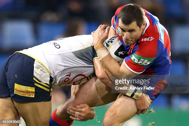 James McManus of the Knights is tackled by the Cowboys defence during the round 15 NRL match between the Newcastle Knights and the North Queensland...