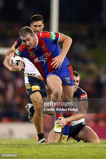 Chris Houston of the Knights is tackled by the Cowboys defence during the round 15 NRL match between the Newcastle Knights and the North Queensland...