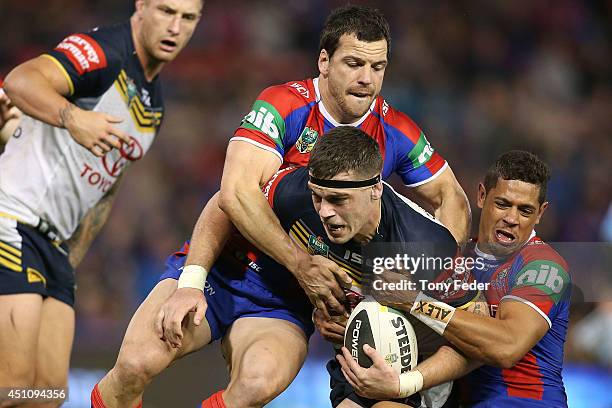 Ethan Lowe of the Cowboys is tackled by Jarrod Mullen and Dane Gagai of the Knights during the round 15 NRL match between the Newcastle Knights and...