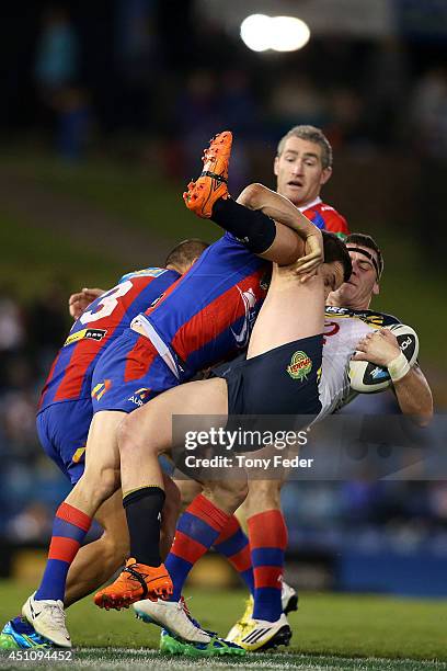 Ethan Lowe of the Cowboys is tackled by the Knights defence during the round 15 NRL match between the Newcastle Knights and the North Queensland...