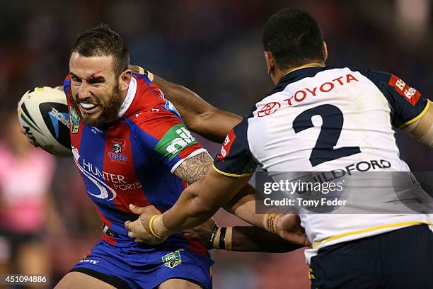 Darius Boyd of the Knights is tackled by Matthew Wright of the Cowboys during the round 15 NRL match between the Newcastle Knights and the North...