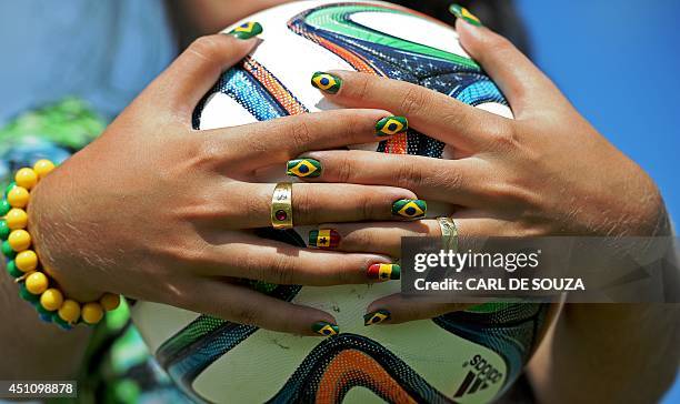 Woman with fingernails painted with the flag symbols of Brazil and Ghana holds the official World Cup ball - Brazuca - at the Rei Pele stadium in...