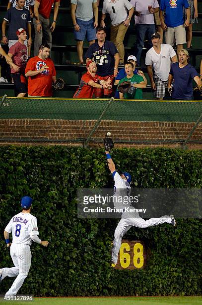 Center fielder Justin Ruggiano of the Chicago Cubs leaps for a grand slam hit by Devin Mesoraco of the Cincinnati Reds as left fielder Chris Coghlan...