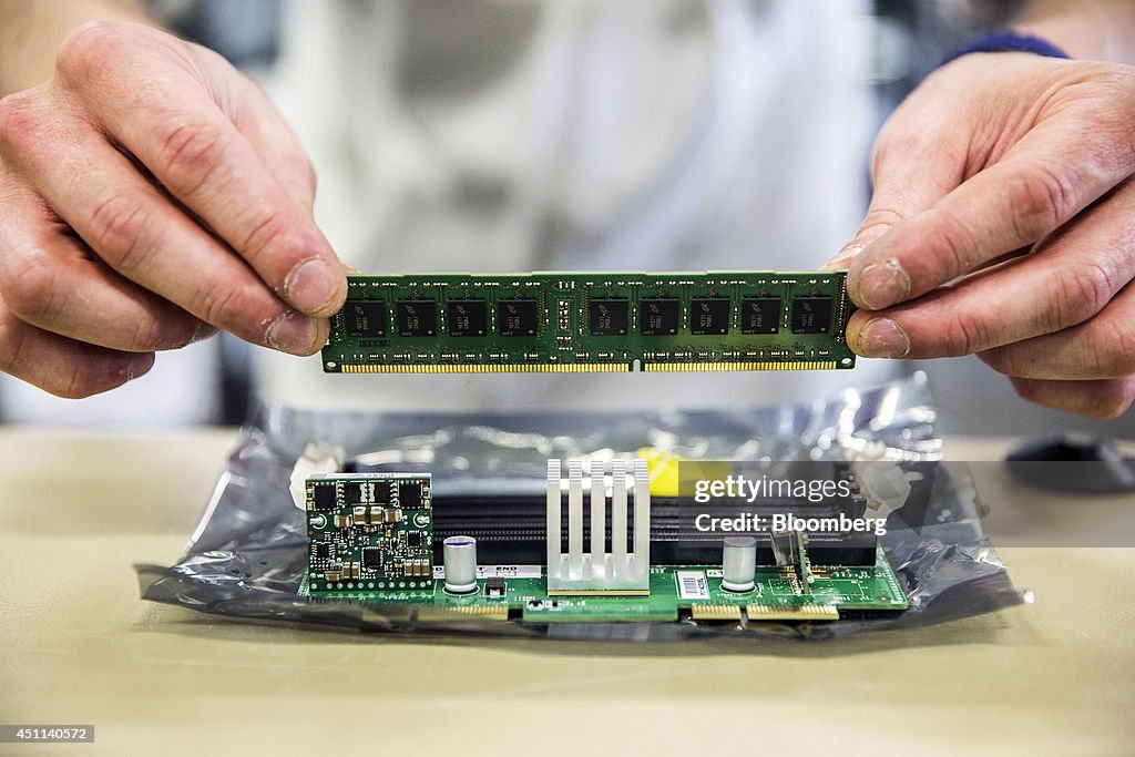 A technician inserts a random access memory board into a slot on a ...
