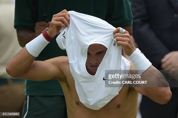 Spain's Rafael Nadal changes his shirt between games against Slovakia's Martin Klizan during their men's singles first round match on day two of the...