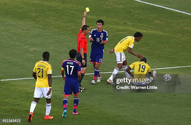 Referee Pedro Proenca shows a yellow card to Yasuyuki Konno of Japan during the 2014 FIFA World Cup Brazil Group C match between Japan and Colombia...
