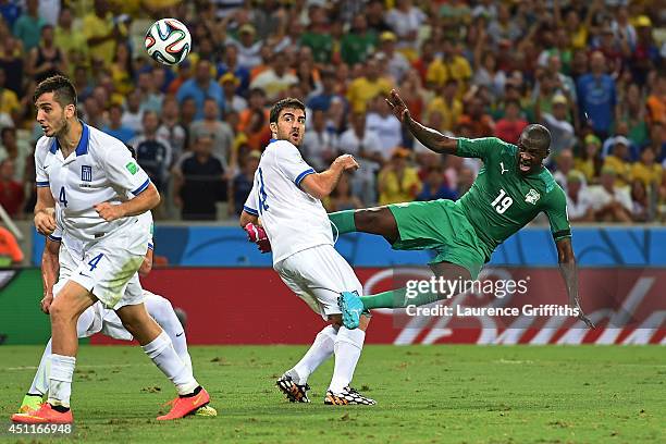 Yaya Toure of the Ivory Coast shoots against Sokratis Papastathopoulos of Greece during the 2014 FIFA World Cup Brazil Group C match between Greece...