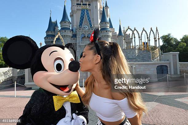 In this handout photo provided by Disney Parks, singer Ariana Grande gives Mickey Mouse a kiss in front of Cinderella Castle in the Magic Kingdom...