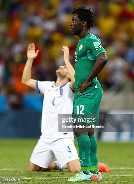 Dejected Wilfried Bony of the Ivory Coast looks on as Konstantinos Manolas of Greece celebrates during the 2014 FIFA World Cup Brazil Group C match...