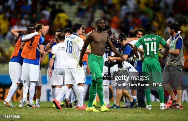 Sol Bamba of the Ivory Coast walks off the pitch while Greece players celebrate after the 2014 FIFA World Cup Brazil Group C match between Greece and...