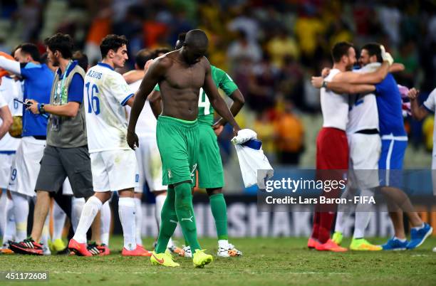 Sol Bamba of the Ivory Coast walks off the pitch while Greece players celebrate after the 2014 FIFA World Cup Brazil Group C match between Greece and...