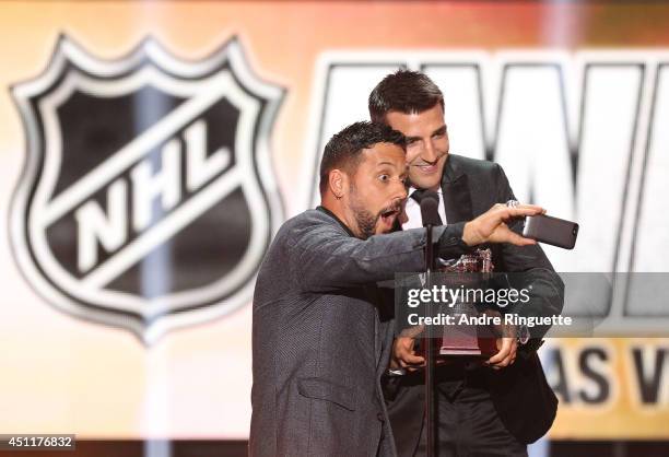 Canadian television and radio personality George Stroumboulopoulos takes a selfie photo with Patrice Bergeron of the Boston Bruins after Bergeron won...