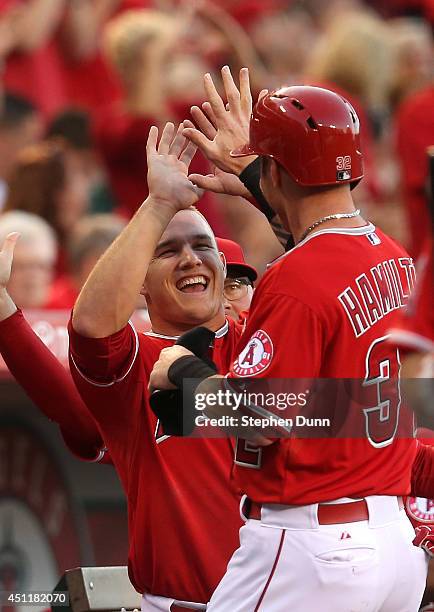 Mike Trout of the Los Angeles Angels of Anaheim greets Josh Hamilton as Hamilton returns the dugout after scoring a run in the first inning against...