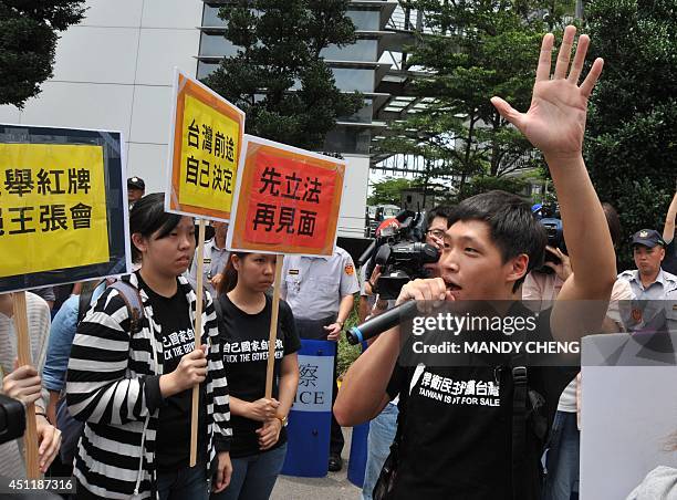 One of the student protest leaders Chen Wei-ting speaks as a group of demonstrators hold placards outside the hotel near the airport in Taoyuan where...