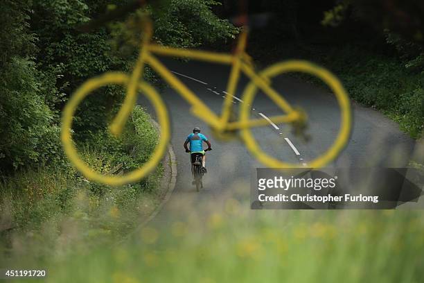 Cyclist rides the route of the Tour De France past a yellow bicycle hanging from a tree as Yorkshire prepares to host the Tour de France Grand...