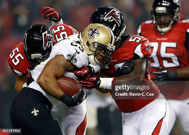 Running back Pierre Thomas of the New Orleans Saints is tackled by outside linebacker Paul Worrilow and middle linebacker Akeem Dent of the Atlanta...
