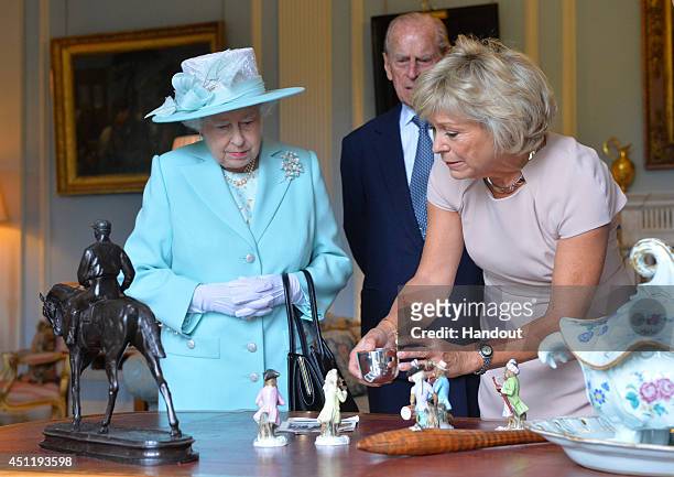 In this handout image provided by Harrison Photography, Queen Elizabeth II and Prince Philip, Duke of Edinburgh talk to Antiques Roadshow expert...