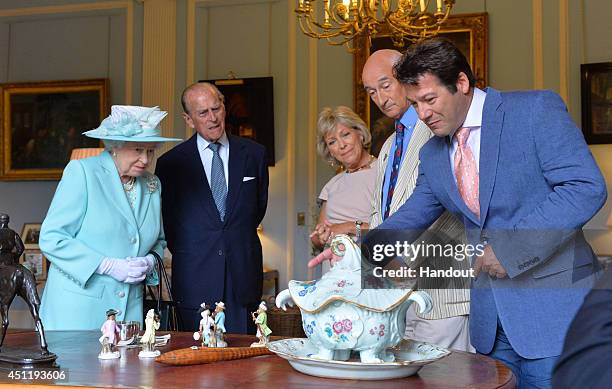 In this handout image provided by Harrison Photography, Queen Elizabeth II and Prince Philip, Duke of Edinburgh talk to Antiques Roadshow experts...