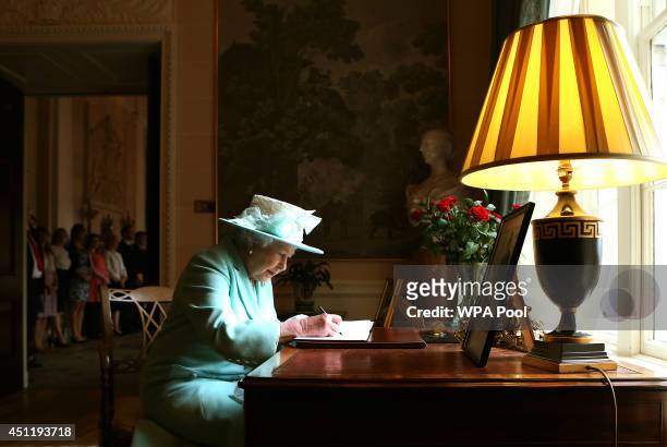 Queen Elizabeth II signs the visitor book prior to departing Hillsborough Castle, on the third and final day of the Queen's visit to Northern...