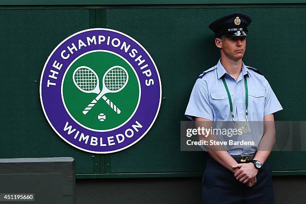 Security Guard is seen standing next to the Wimbledon logo on day three of the Wimbledon Lawn Tennis Championships at the All England Lawn Tennis and...