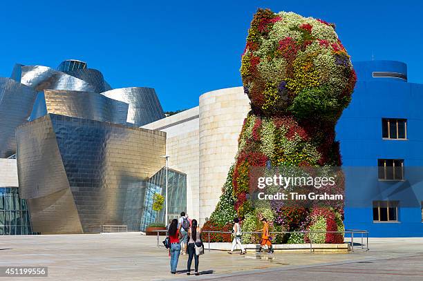 Tourists view Puppy flower feature floral art by Jeff Koons at Guggenheim Museum in Bilbao, Basque Country, Spain