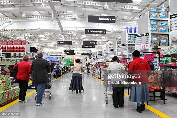 Customers push shopping carts along an aisle past homewares inside a Makro cash and carry store, operated by Massmart Holdings Ltd., in Alberton,...