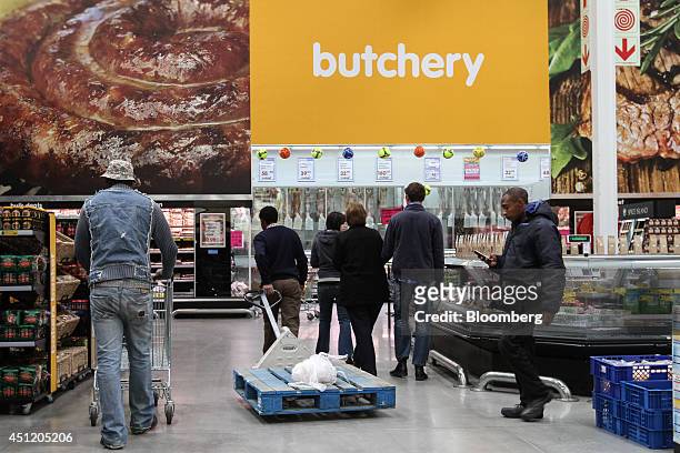 Shoppers browse the aisles beneath a butchery sign in the meat section of a Makro cash and carry store, operated by Massmart Holdings Ltd., in...