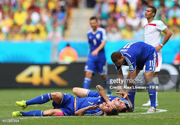 Muhamed Besic of Bosnia and Herzegovina and his teammate Toni Sunjic lie on the ground injured after colliding while Edin Dzeko help them during the...