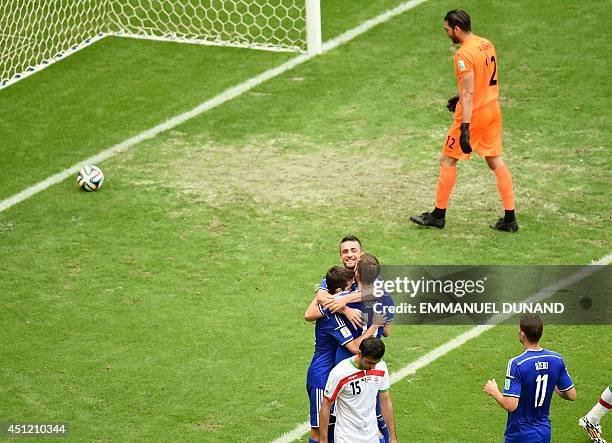 Bosnia-Herzegovina's midfielder Miralem Pjanic celebrates scoring his team's second goal with team-mates as Iran's goalkeeper Alireza Haghighi and...