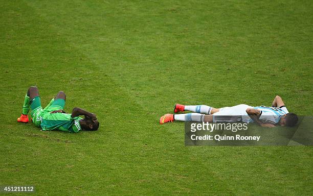 Juwon Oshaniwa of Nigeria and Ricardo Alvarez of Argentina lie on the field after a collision during the 2014 FIFA World Cup Brazil Group F match...