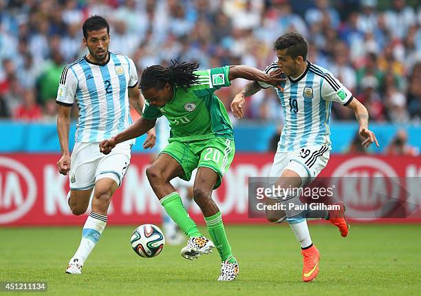 Okechukwu Uchebo of Nigeria controls the ball against Ezequiel Garay and Ricardo Alvarez of Argentina during the 2014 FIFA World Cup Brazil Group F...
