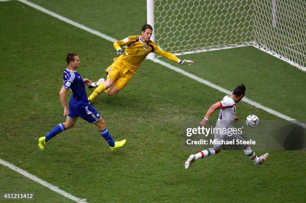 Reza Ghoochannejhad of Iran shoots and scores his team's first goal past goalkeeper Asmir Begovic of Bosnia and Herzegovina during the 2014 FIFA...